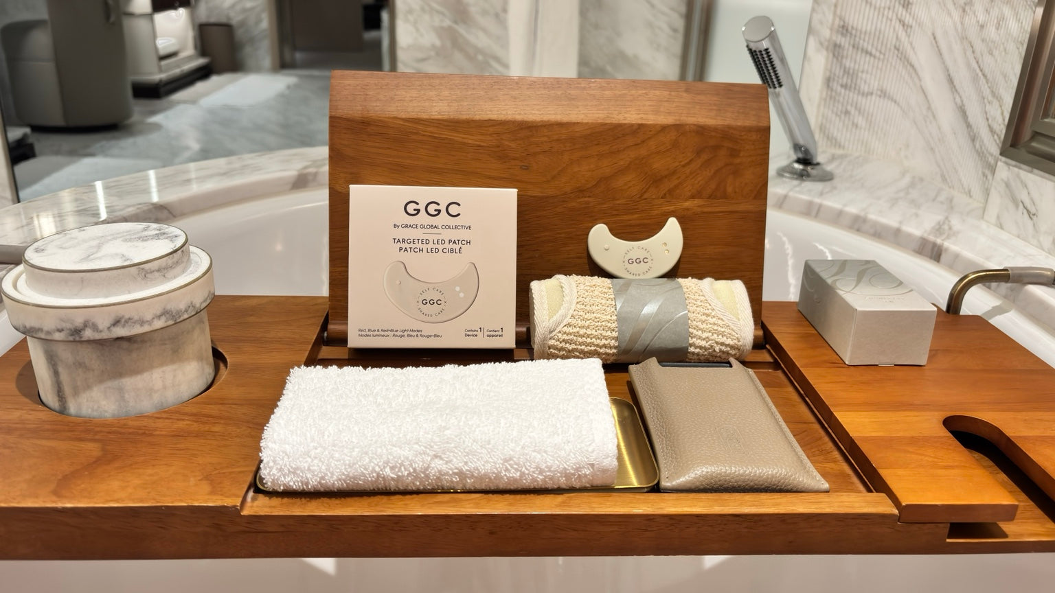 GGC packaging and LED patch on a wooden bath tray with towels in a marble bathroom