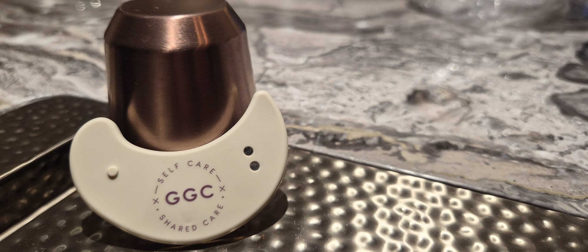 GGC LED patch leaning against a bronze vessel on a textured metal tray