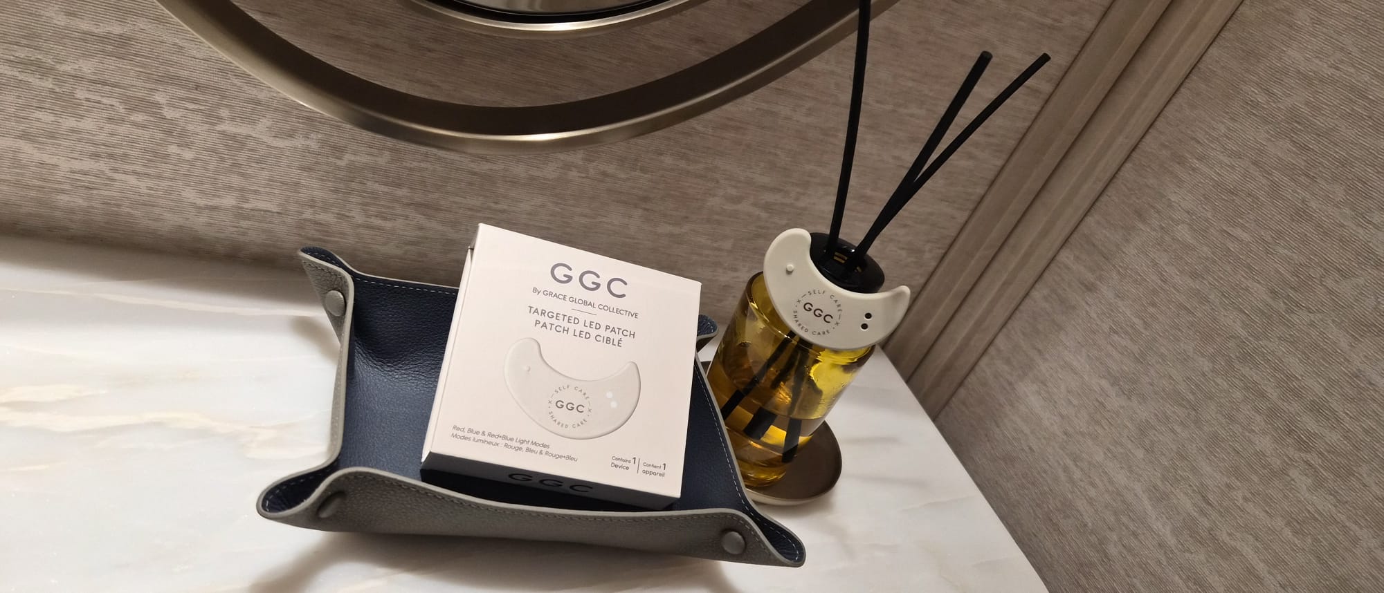 GGC packaging in a leather tray and LED patch beside a reed diffuser
